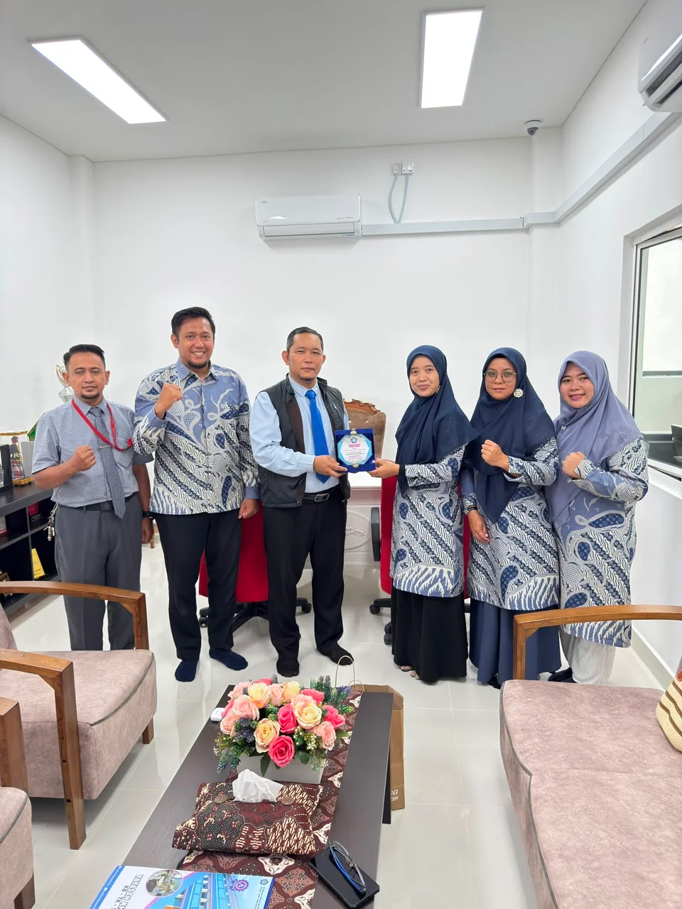 Foto bersama sambil memegang cendera mata dalam kunjungan pendidikan.